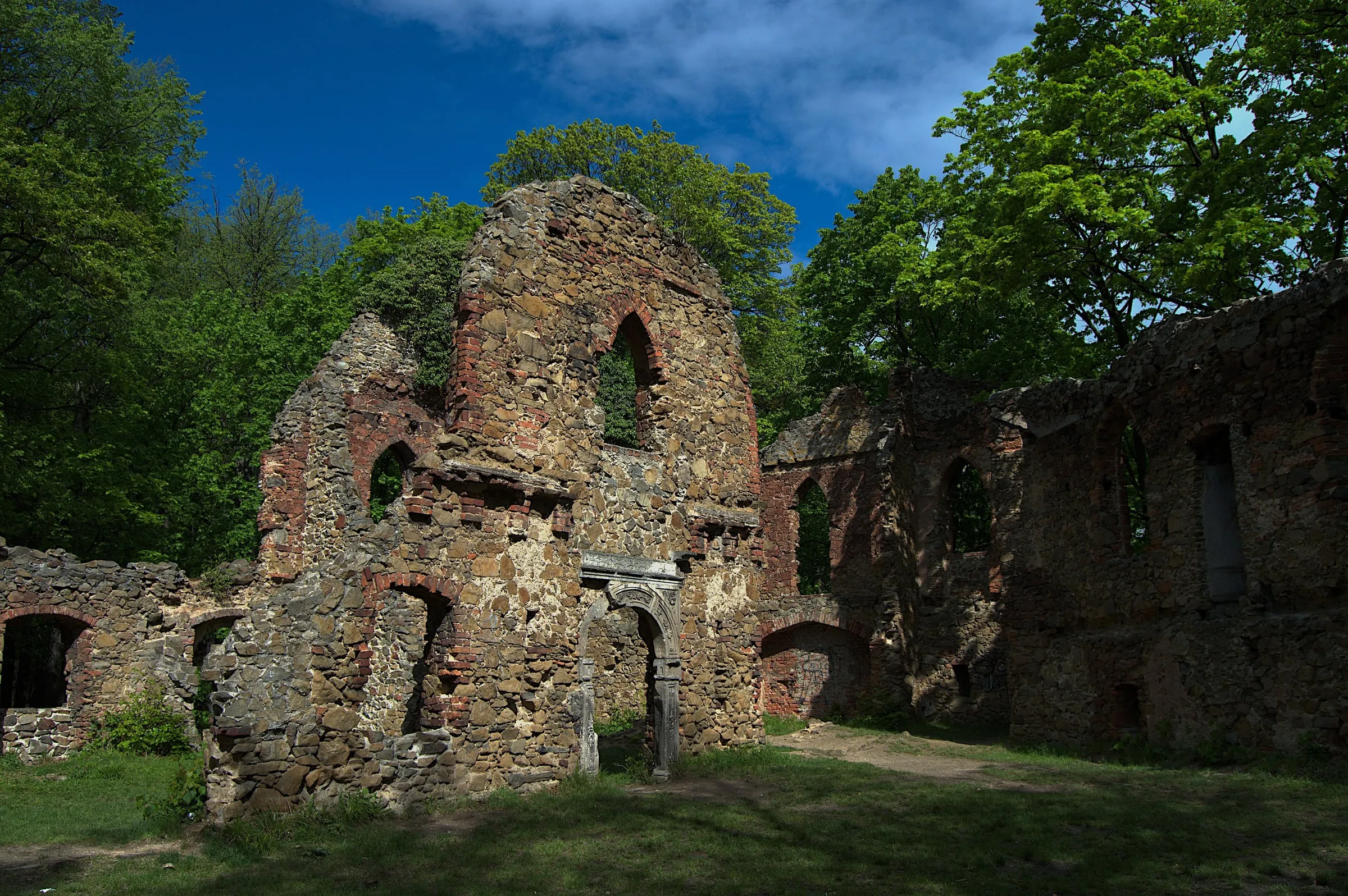 Dziedziniec ruin Starego Książa z ostrołukowymi oknami i renesansowym portalem wiosną