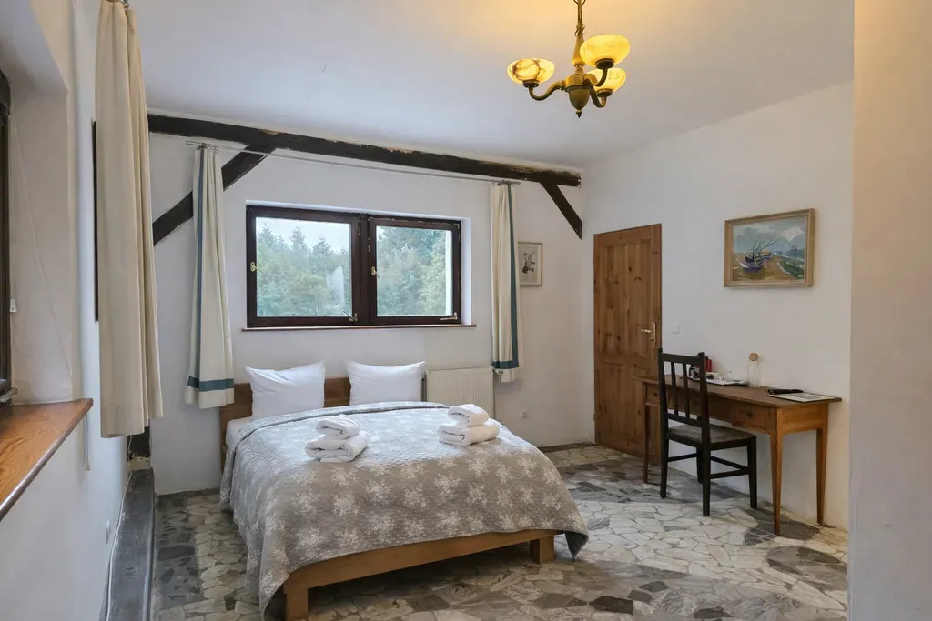 Doppelzimmer mit Doppelbett, Kronleuchter und Blick in den Wald